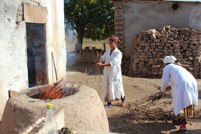 men in white are making fire in a hut