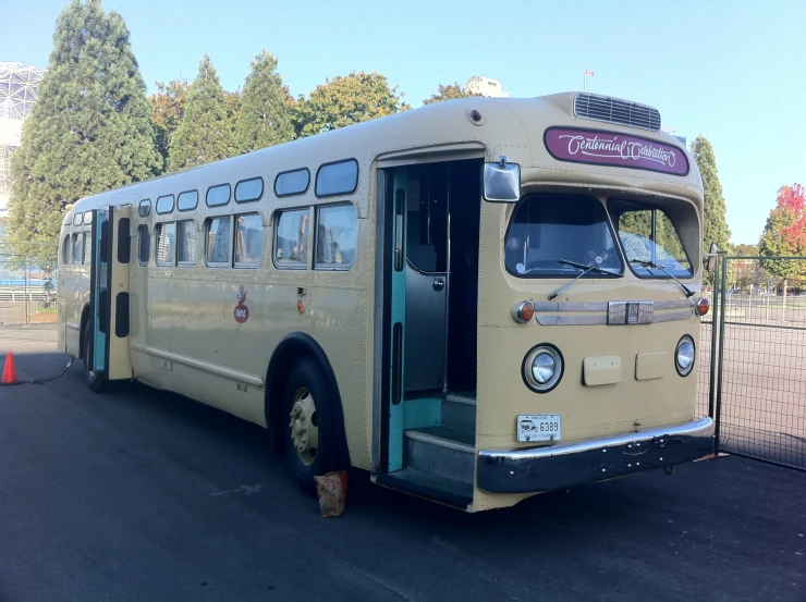 the large bus is parked behind a fence