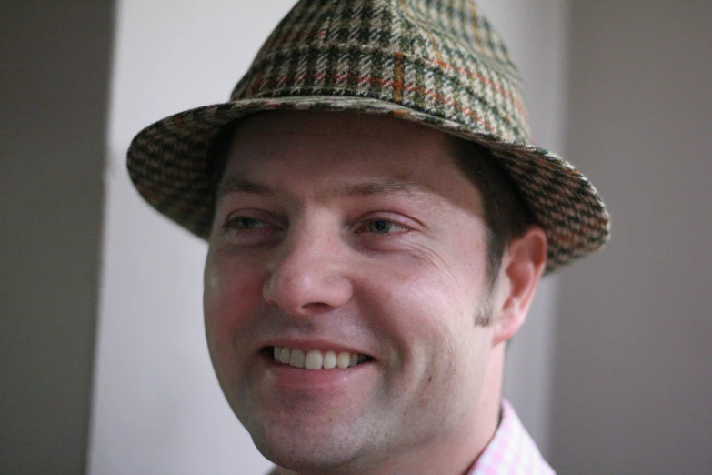 a man in a hat and dress shirt with a pink shirt