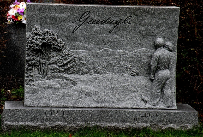 a monument sits with a small statue and flowers