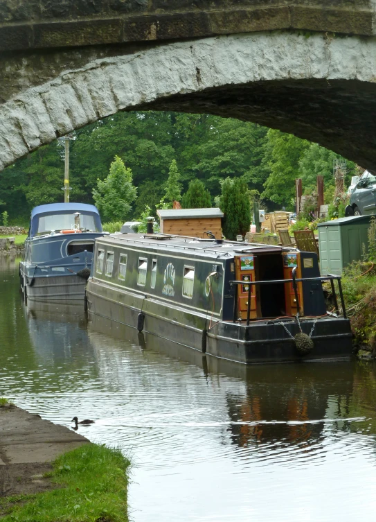 two boats tied up next to each other by a bridge