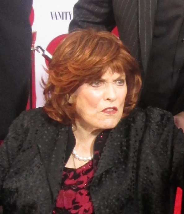 a woman with her head tilted looking at soing while sitting in front of a group of people