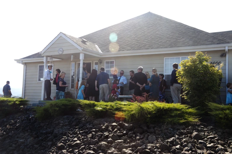 group of people standing outside a house by the ocean