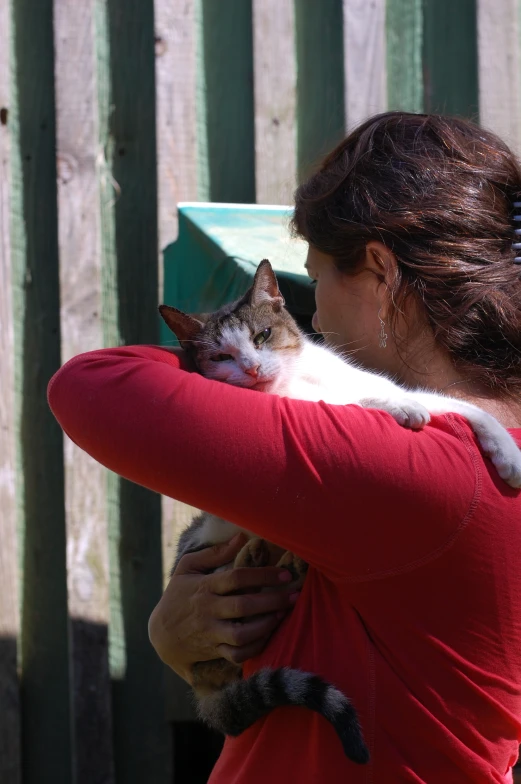a woman is holding a cat in her arms