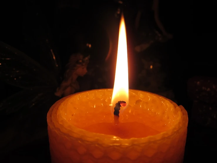 a bright orange candle is lit on a table