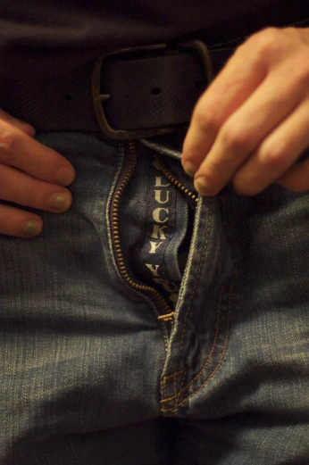 person putting pocket in their jeans while wearing an unoned shirt