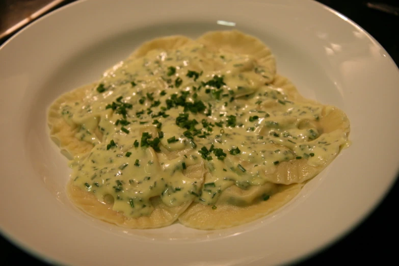 a white plate topped with ravioli and green sauce