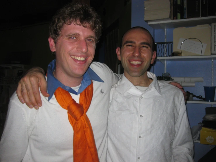 two men standing next to each other smiling at the camera