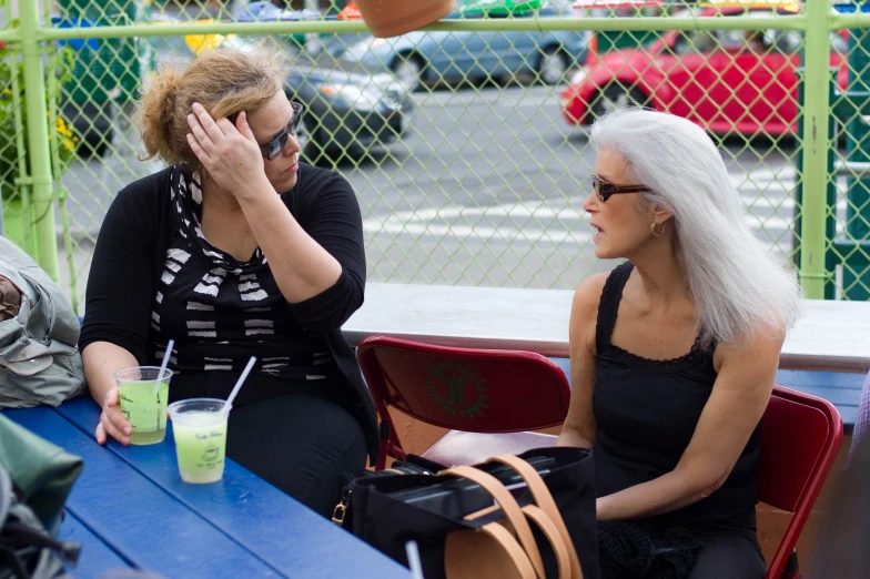 two women sitting on top of a blue table next to each other