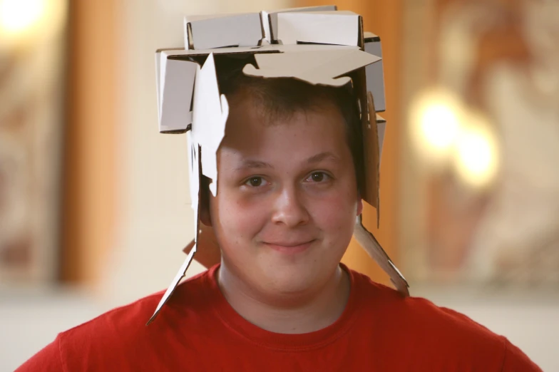 a boy with a cardboard box shaped like a head and some silver scissors