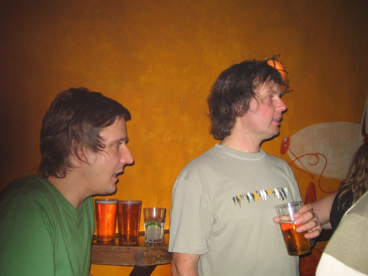 two young men drinking beer next to each other