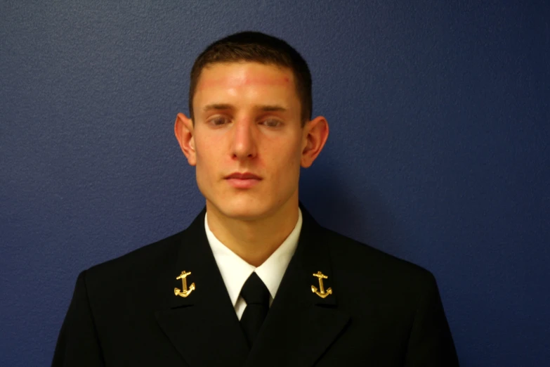 a man in a military uniform, standing in front of a blue wall