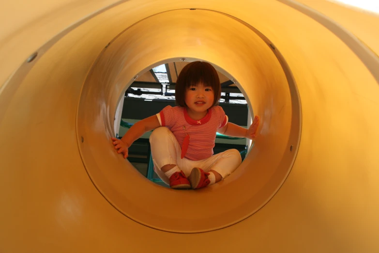 a little girl sitting in the middle of a slide