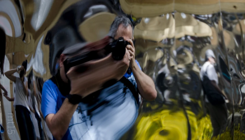 a man holding a camera up next to a painting