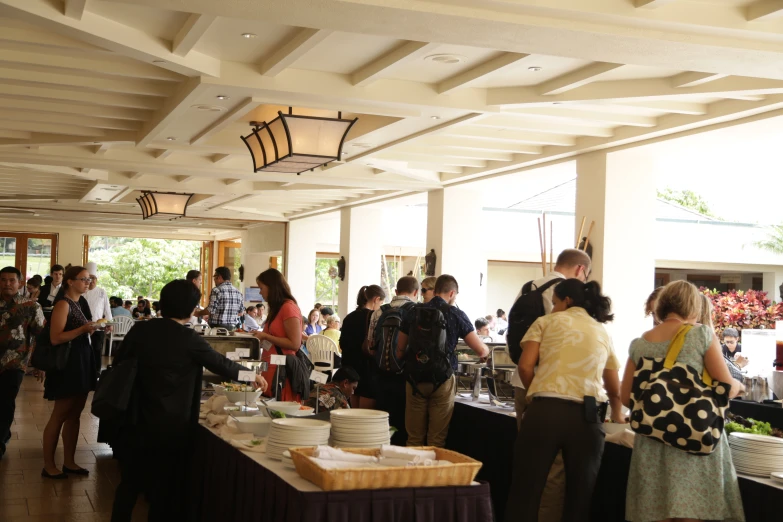 a room full of people in dress and with plates of food on tables