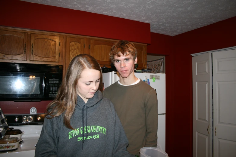 two people standing in the kitchen near the refrigerator