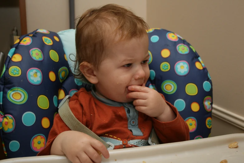 a young baby in a booster seat eating food