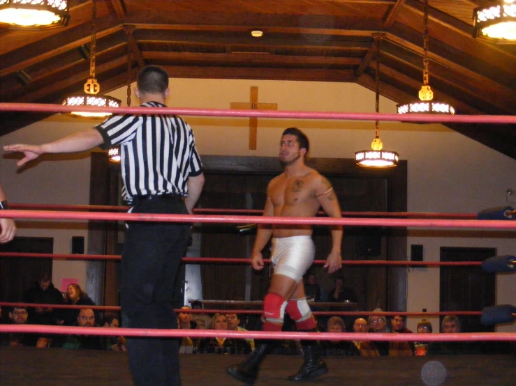 two men in wrestling gloves stand in an indoor arena