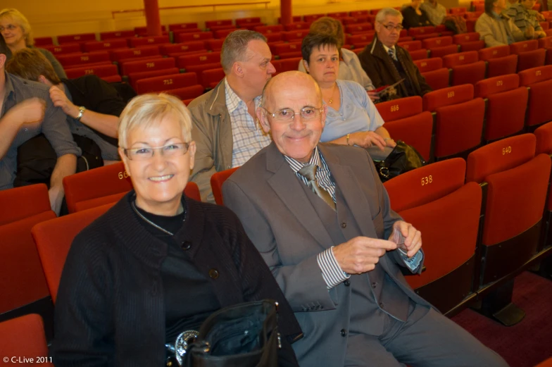 a man and woman sitting in rows of seats