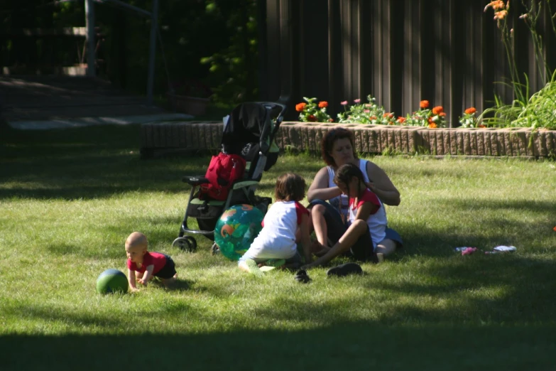 a woman and two small children sitting on the grass