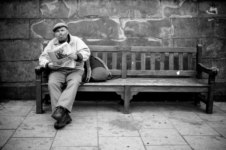 a man in a hat sits on a wooden bench