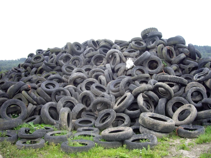 a pile of tires stacked up on top of a lush green field