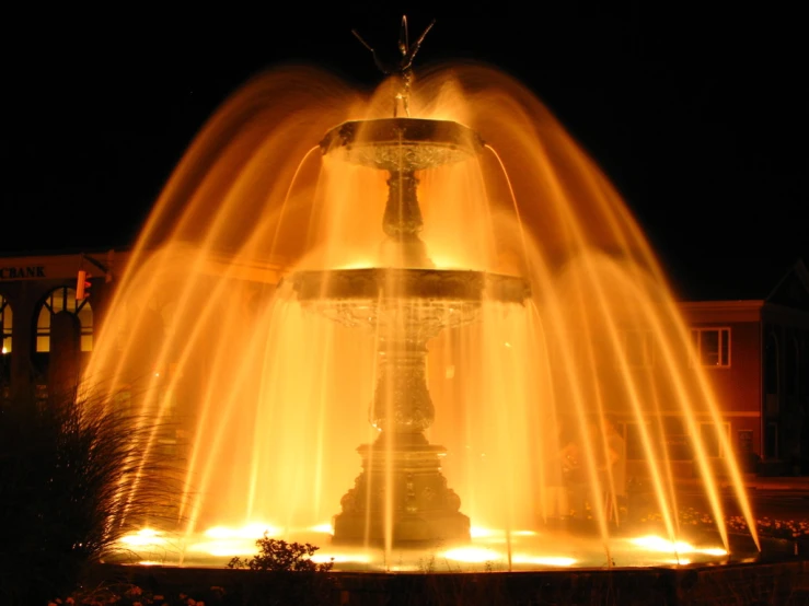 a lighted fountain with water spewing from it