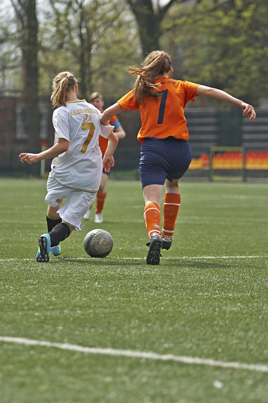 three s playing a game of soccer on a soccer field