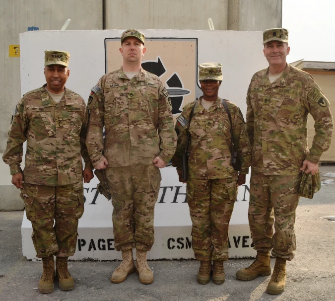 three men in uniform standing by a sign