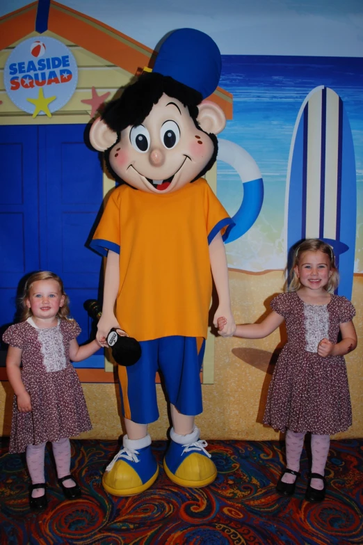 children with the blue squad mascot posing in front of it