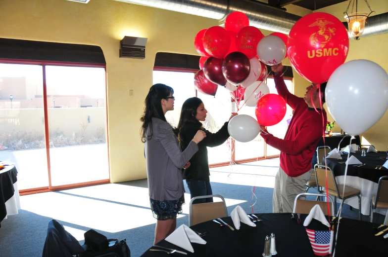 a couple of girls holding onto red, white, and white balloons