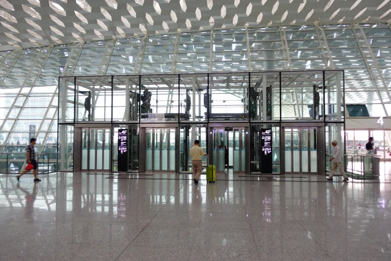 people entering and exiting a large building with clear doors