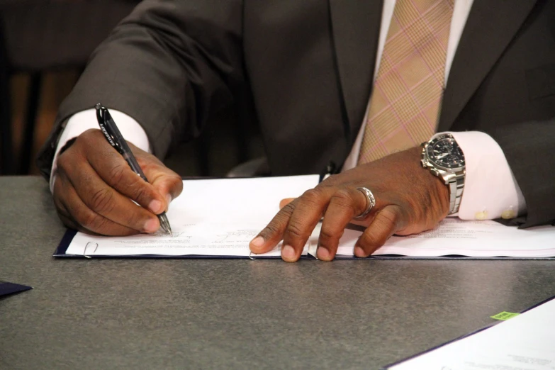 a black man in a suit and tie is holding a pen