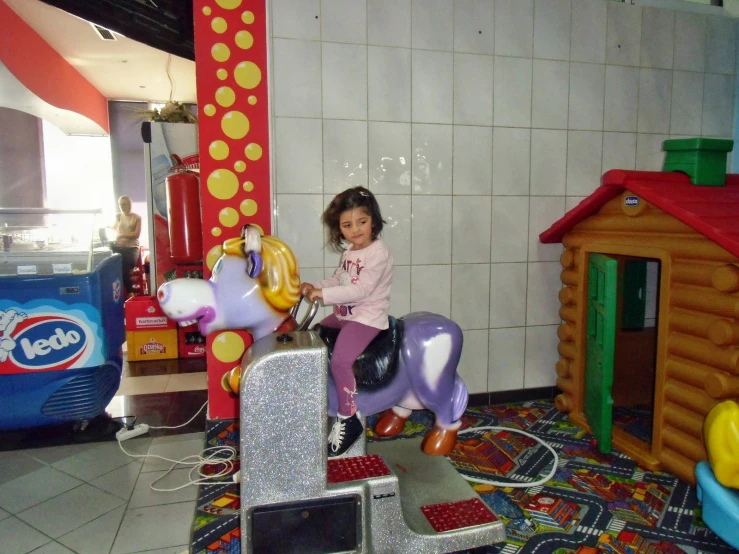 a little girl plays on an animal ride at a toy store