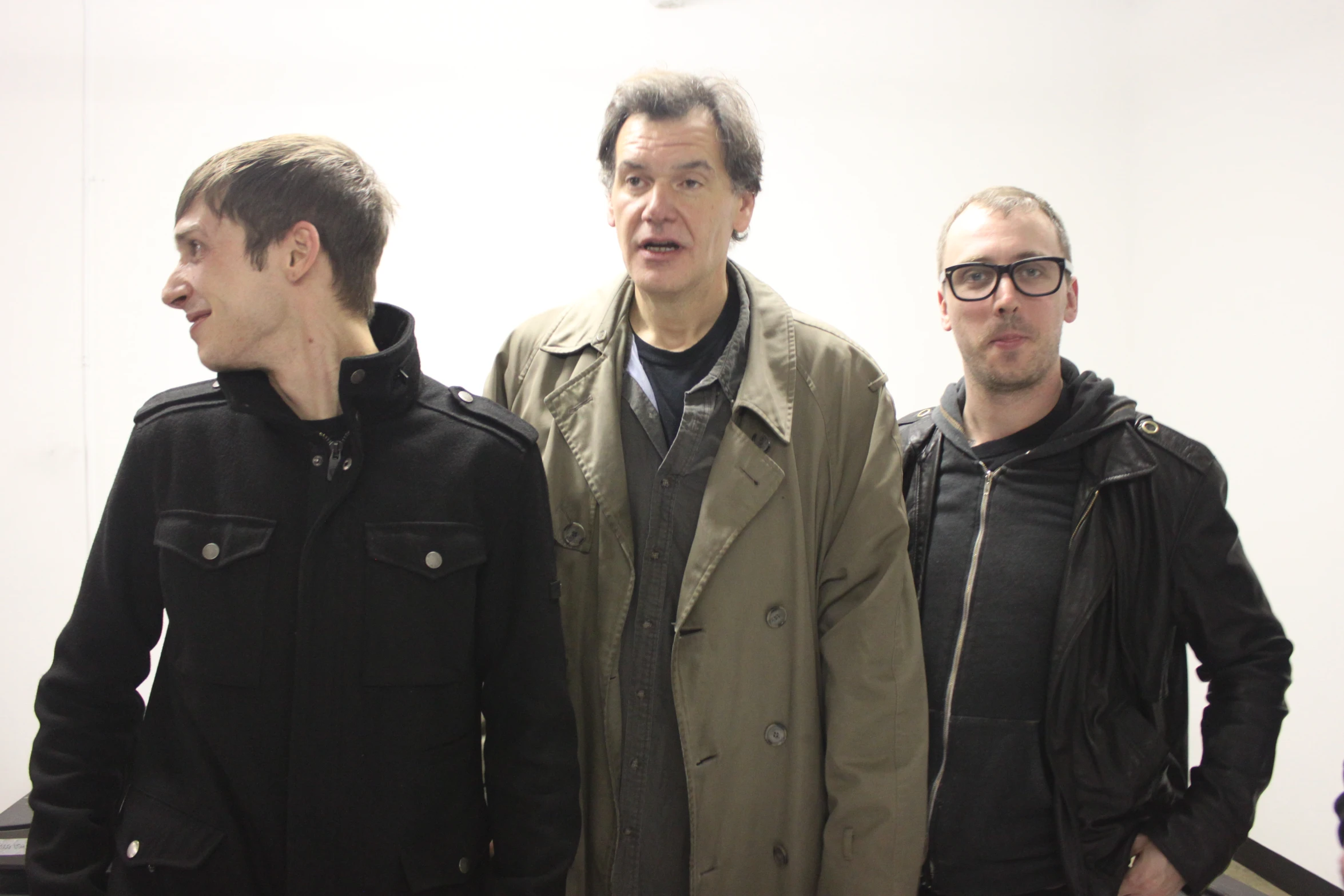 three men are standing side by side and wearing a jacket