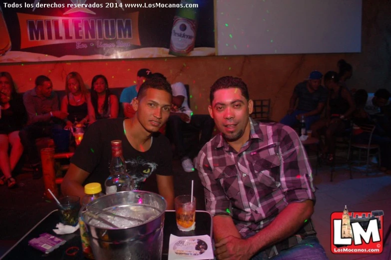 two men pose for the camera as they hold drinks