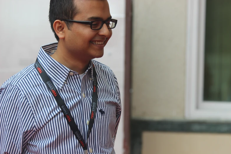 a smiling man with eye glasses and a lanyard