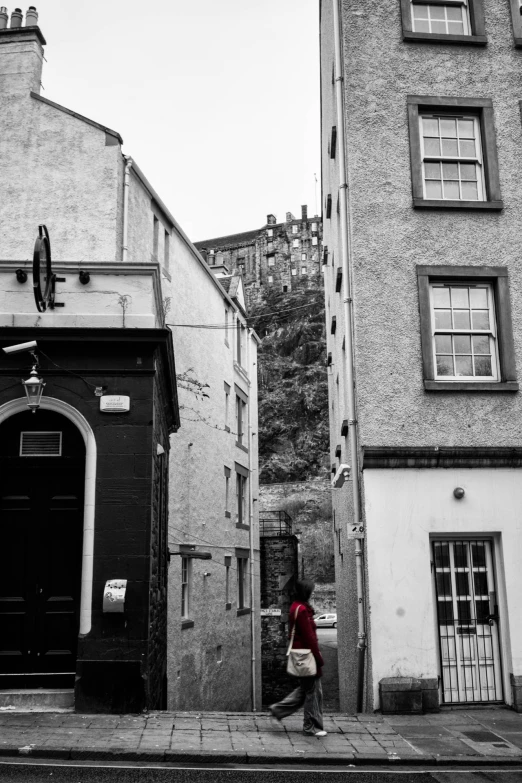 an old building with lots of windows is behind the woman in the red shirt