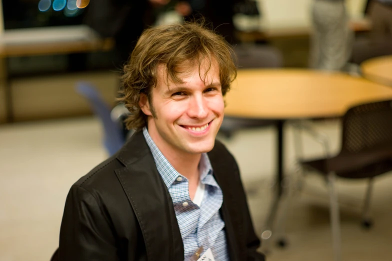 a man smiling in front of some tables