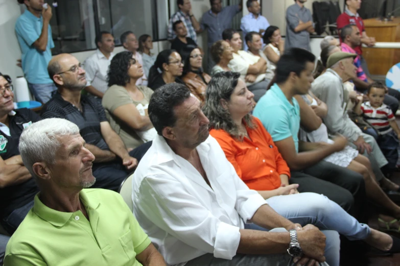 a crowd is in a large building, one person sitting in the front row