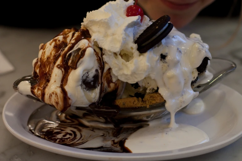 a woman in the foreground, a plate filled with ice cream and chocolate covered cookie