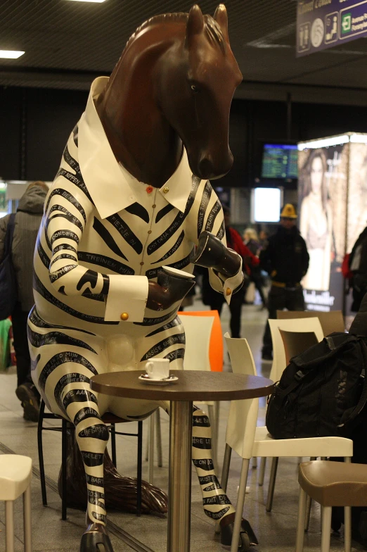 the life - sized horse sits on a chair at a table