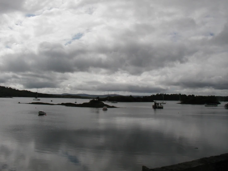a body of water with clouds overhead and several boats out on it