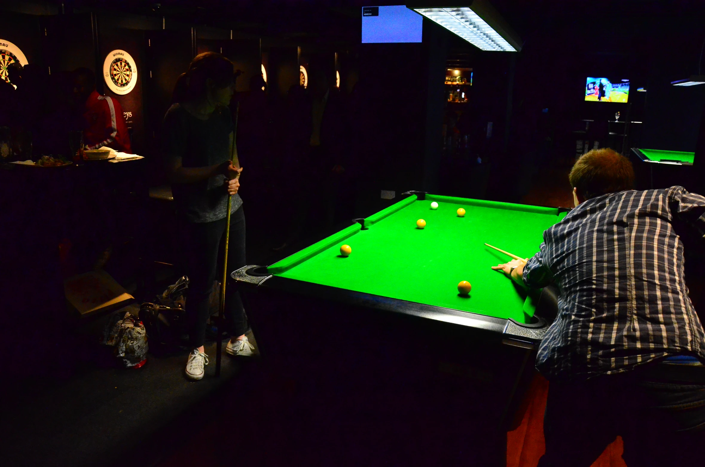 two people play pool while others watch