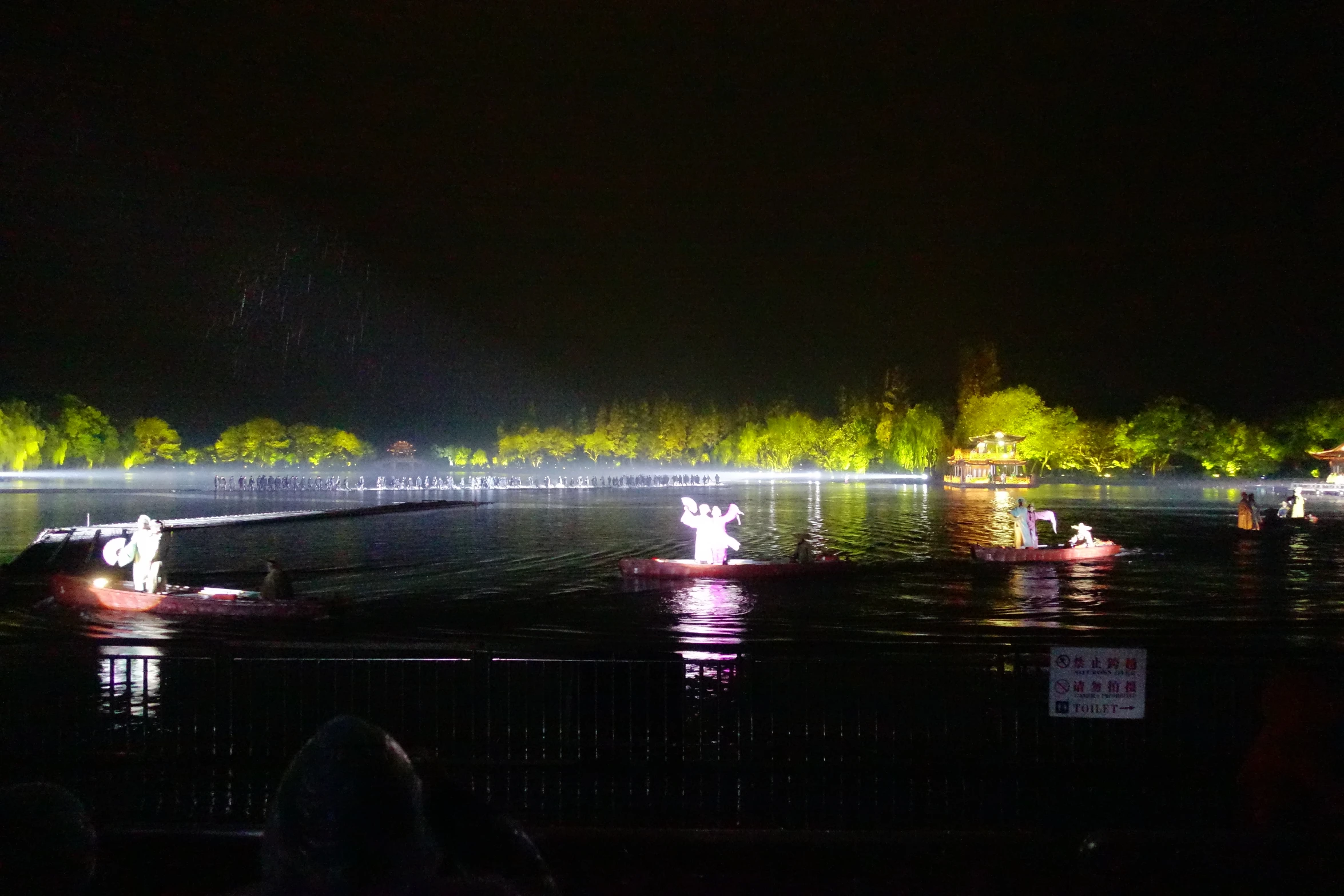 boaters in boats are illuminated by light on a night