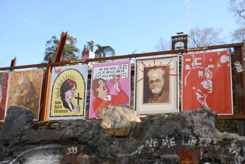 several posters on the wall below the fence