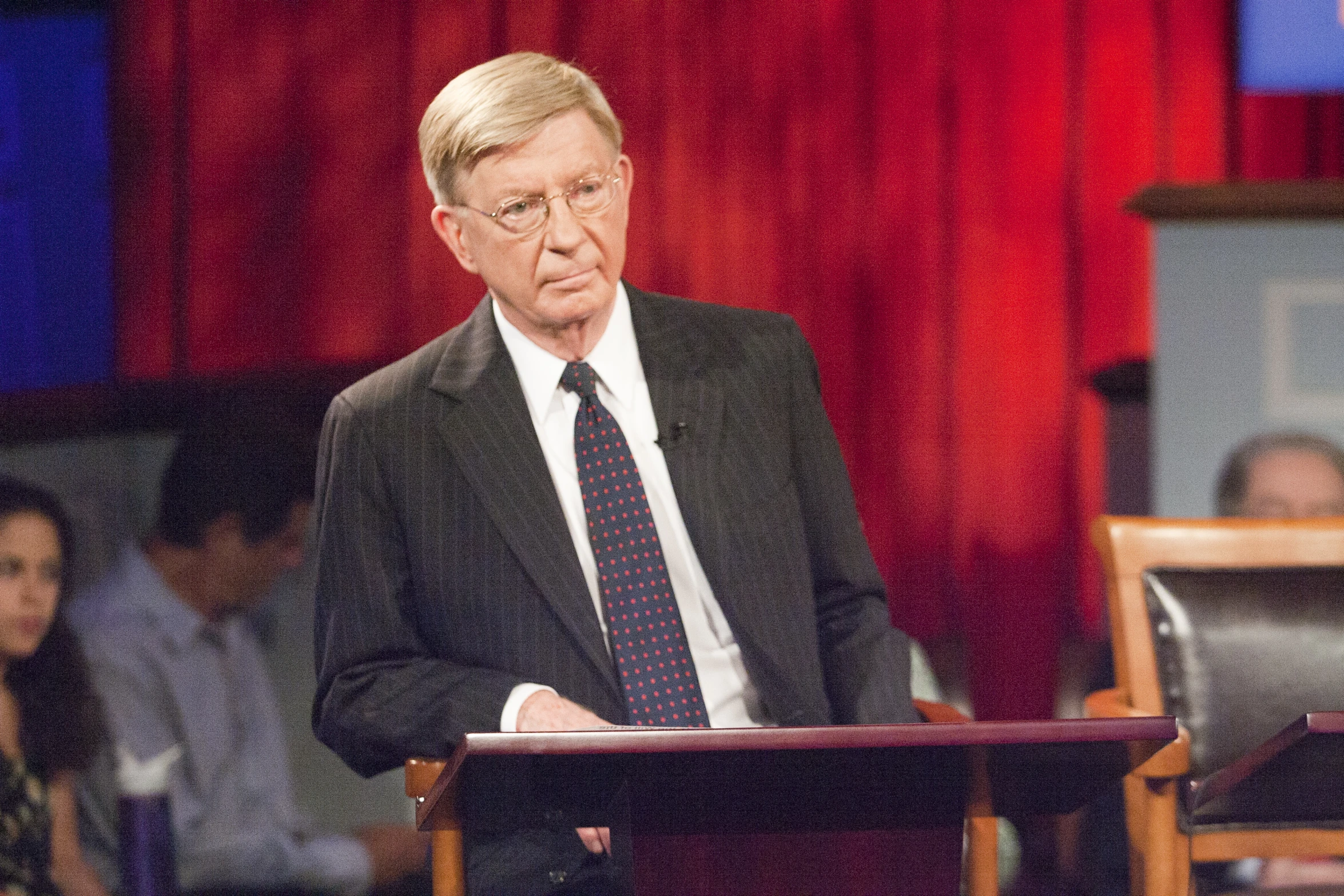 a man wearing glasses is at a podium