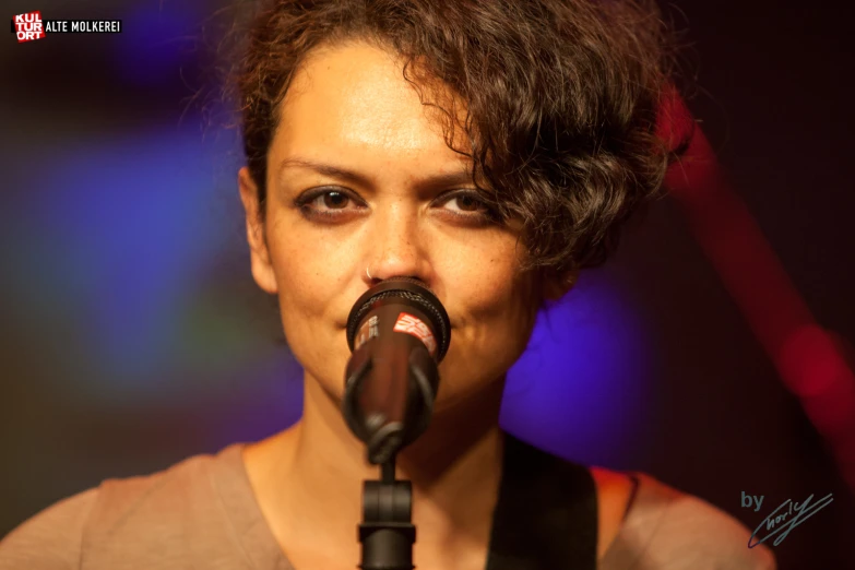 the woman with short hair is singing into a microphone