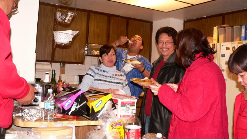 people standing in a kitchen and eating food