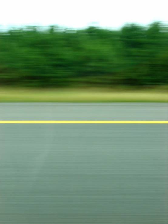 an blurry picture of a green, grassy area on the side of a road